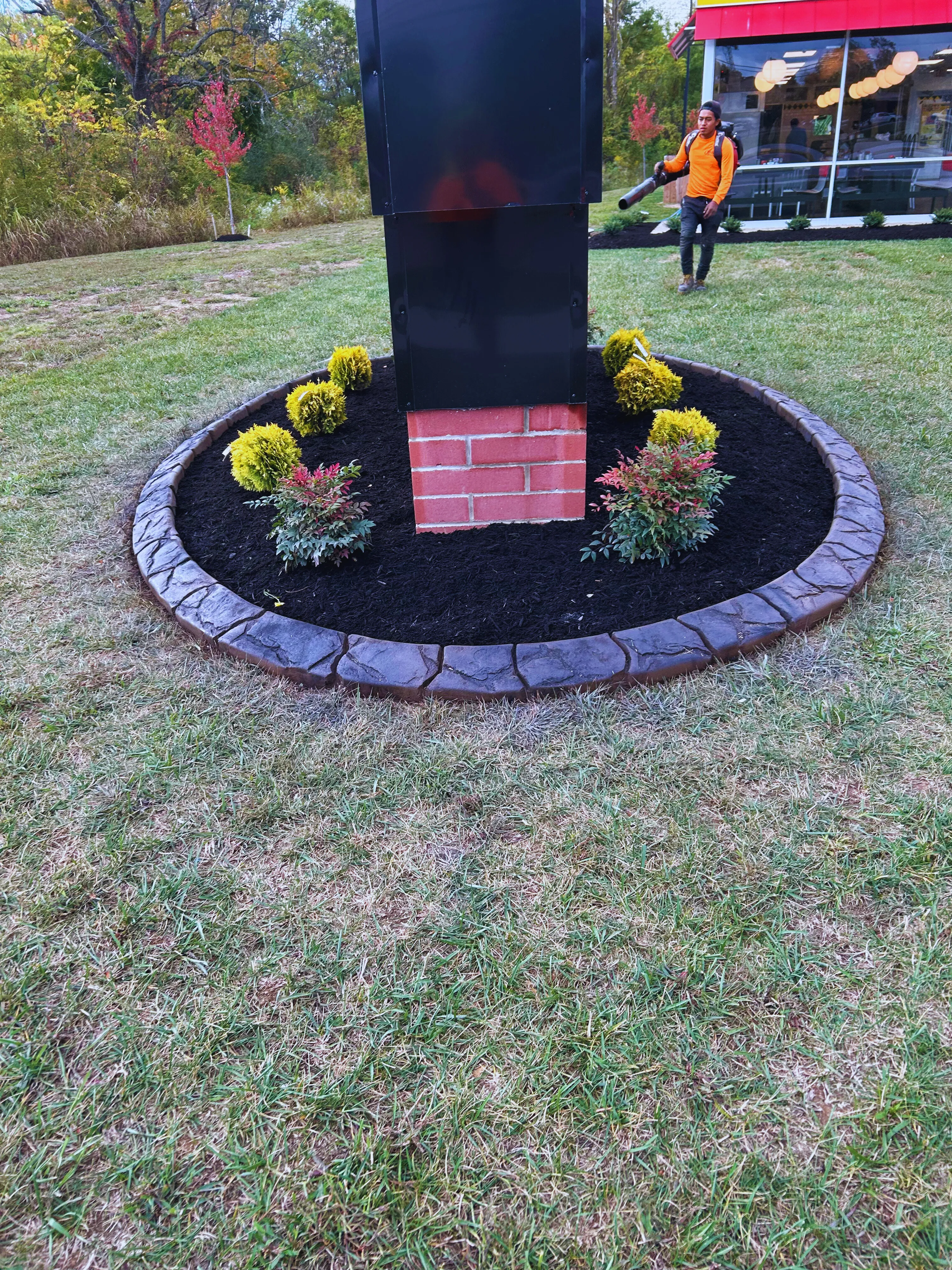 Round stamped-concrete bed around a commercial monument from a different angle