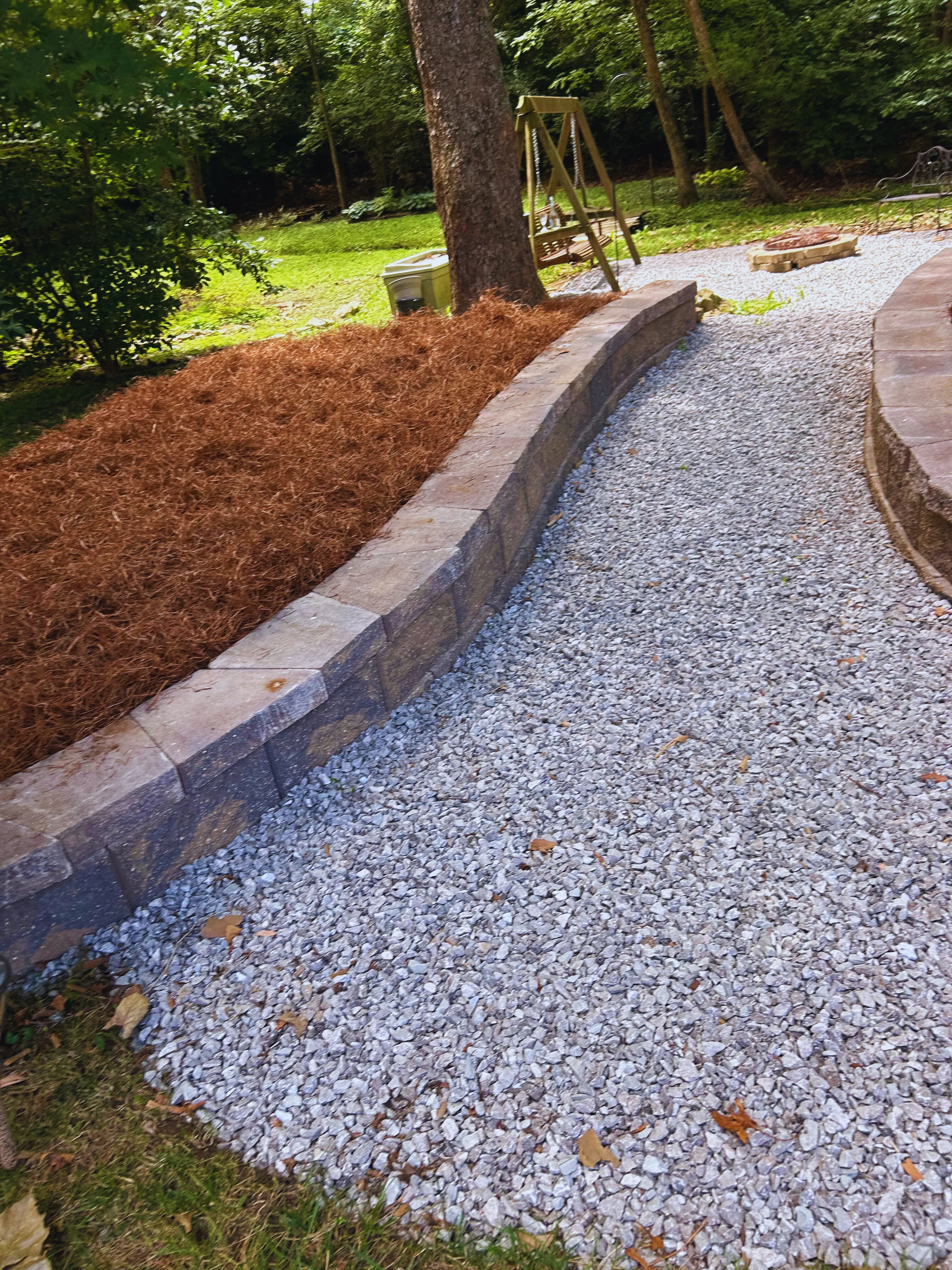 Curved stone retaining wall around a tree with a garden statue, a recent hardscaping job